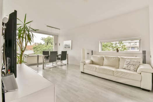 A contemporary living room featuring a white aesthetic, modern furniture, and ample natural light, creating a spacious and inviting atmosphere.