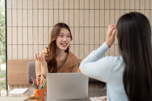 Two students share ideas and notes while studying together, mutually supporting their academic growth in a vibrant cafe setting.
