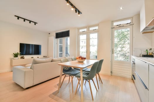 A stylish living room featuring a cozy sofa, a dining table, and large windows that allow plenty of natural light, creating an inviting atmosphere.