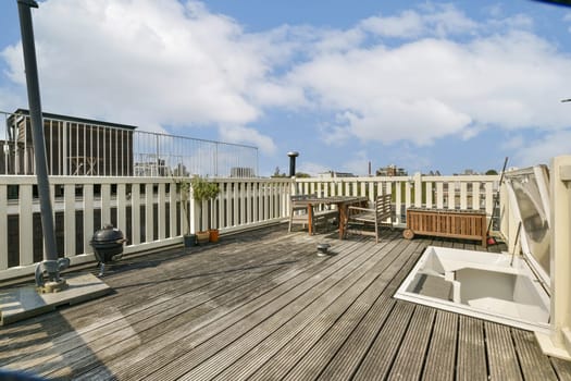 A bright rooftop terrace featuring wooden flooring, planters, and stylish furniture, ideal for relaxation and enjoying city views on a sunny day.