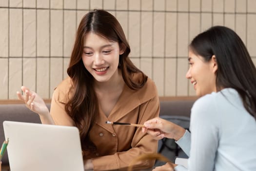 Two female students gather at a cafe, exchanging insights and focusing on their studies together, fostering collaboration and creativity in a lively setting.