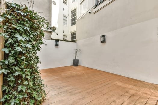An inviting courtyard featuring lush greenery and wooden flooring, creating a tranquil space for relaxation and enjoyment in an urban setting.