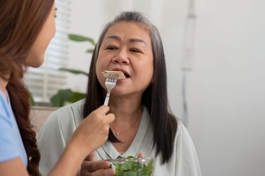 The daughter lovingly feeds her mother a piece of fresh salad, reinforcing their bond while promoting wellness through nutritious eating habits.