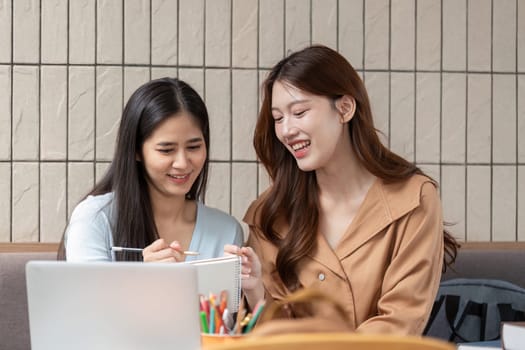 In a cozy cafe, two friends share a light-hearted moment as they study, making the most of their time together while enhancing their understanding through teamwork.