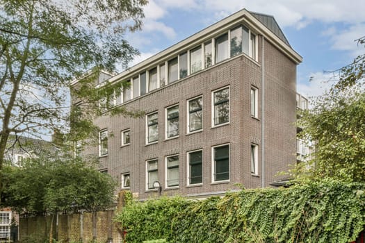 The image showcases a modern brick building with intricate designs and greenery surrounding the base, highlighting contemporary urban architecture.