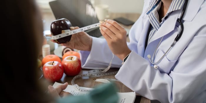 During a one-on-one consultation, a nutritionist engages with a client by measuring an apple, highlighting the significance of understanding food sizes and nutrition.