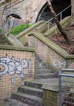 Newcastle, UK - Apr 13, 2025 - Stone stairs and Brick railing with Graffiti leading up under the High level bridge at Newcastle Upon Tyne. use it as your Wallpaper, Poster and Space for text, Selective focus.