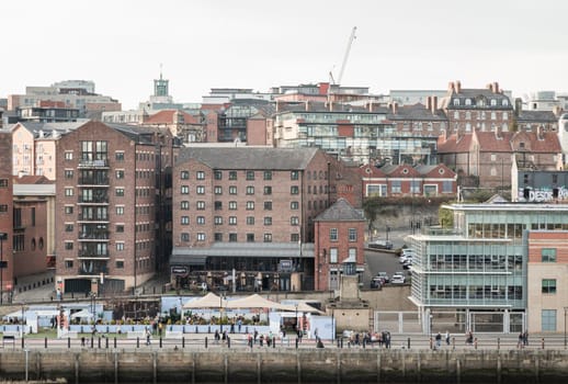 Newcastle, UK - Apr 11, 2025 - Old buildings on the Quayside area and people on the tyneside view from Sage Gateshead (The Glasshouse International Centre for Music) at Newcastle upon Tyne. use it as your Wallpaper, Poster and Space for text, Selective focus