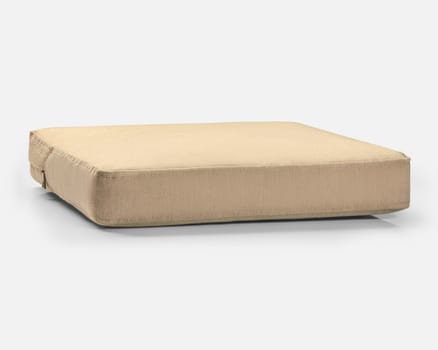 Square beige cushion with visible seams resting on a white surface