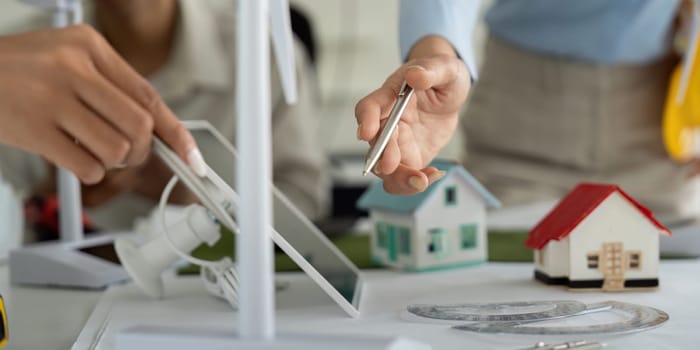 Two professionals collaborate on sustainable building models, sharing insights and technology for green energy design.