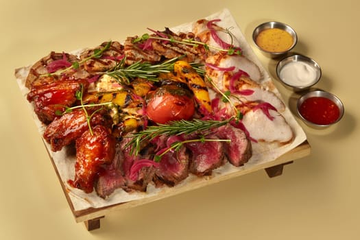 Grilled meat platter featuring chicken wings, beef steak, grilled vegetables, and dipping sauces, creating a visually appealing and flavorful culinary experience