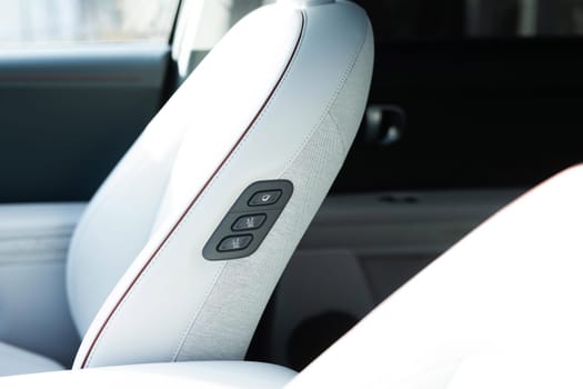 Rear seat passenger switch to control the front passenger seat. Walk-in seat switch. Luxury car interior. Electric car seat position adjustment buttons.