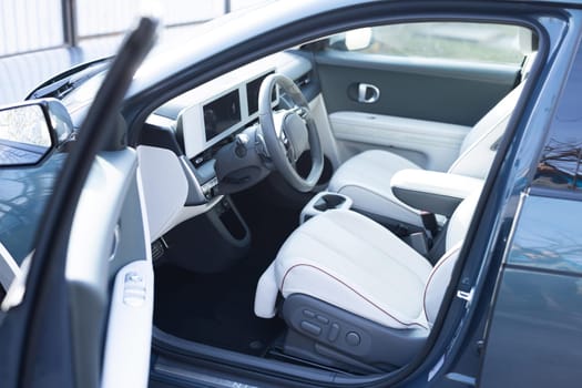 Electric car interior luxury inside. Steering wheel, dashboard, speedometer, display. White leather interior. Modern luxury car Interior - steering wheel, shift lever and dashboard.