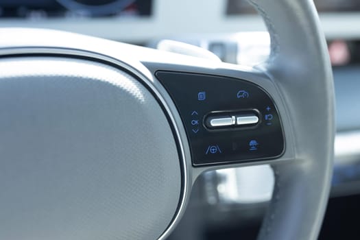 Close up of steering wheel of a new electric vehicle. Electric car control devices. Cruise control buttons, speed limitation, car's signal.