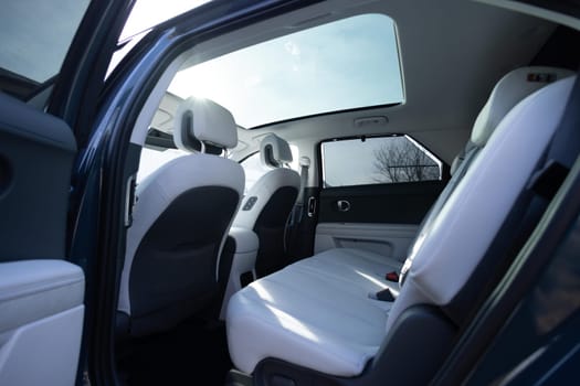 Panoramic glass sun roof in the modern electric car. Clean sunroof and view at the sky from the inside or car interior. The view from the empty car with rear seats.