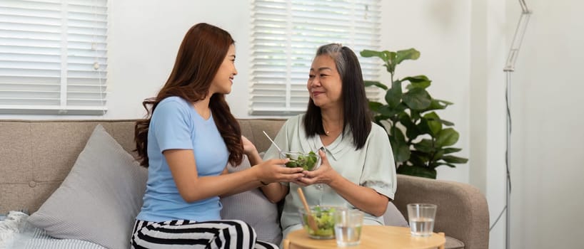 As they share their salads, this mother and daughter duo strengthens their connection, emphasizing healthy living and familial support in a cozy environment.