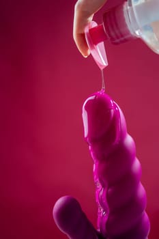 Lube pouring on pink dildo on pink background