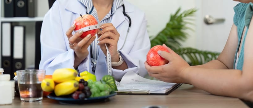 During the consultation, the nutritionist measures the apple to discuss portions, illustrating a comprehensive approach to nutrition in a supportive setting.