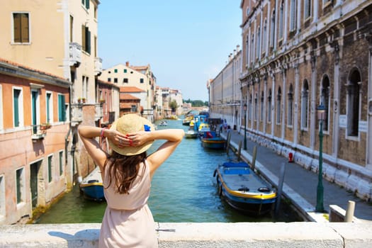 beautiful girl in a hat stands near a canal in Venice, Italy.