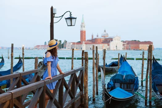 Beautiful sunny Venice, the girl is standing on the bridge near the gondola.