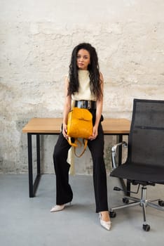A fashionable model confidently showcasing a modern outfit while sporting a vibrant yellow backpack accessory