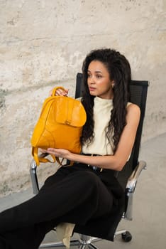 A fashionable model confidently showcasing a modern outfit while sporting a vibrant yellow backpack accessory