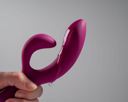 Lube pouring on pink dildo on white background