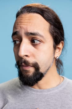 Worried confused guy being shy and insecure with unhappy thoughts, overwhelmed troubled man against blue background. Young person distraught with fear in his eyes, contemplation.