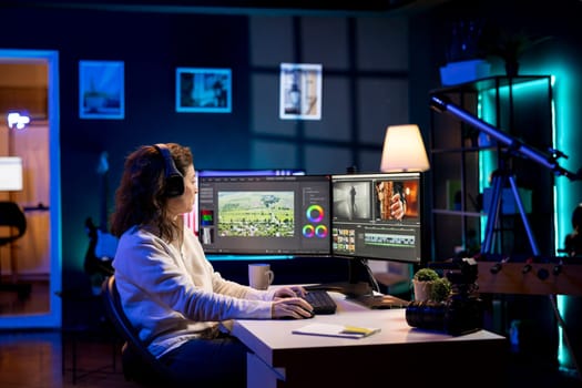 Video editor analyzing film montage before editing color balance and lighting in home studio. Post production studio employee working with raw footage while hearing songs in headphones