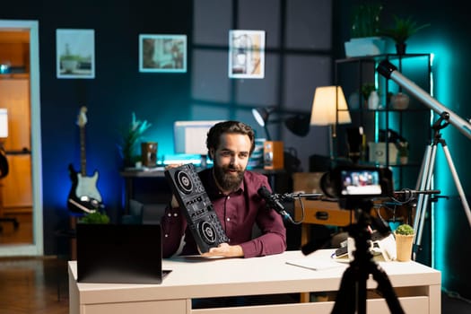 Man filming technology review of DJ controller using professional camera and microphone. Tech guru presenting sound mixer device to audience, recording with high tech equipment