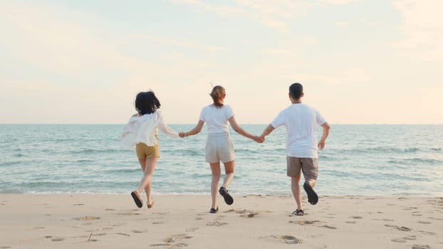 Happy friends holding hands running enjoy life funny and freedom on sand at beach together to sea in holiday vacation time at sunset, Young Asian group woman and man in summer travel, people lifestyle