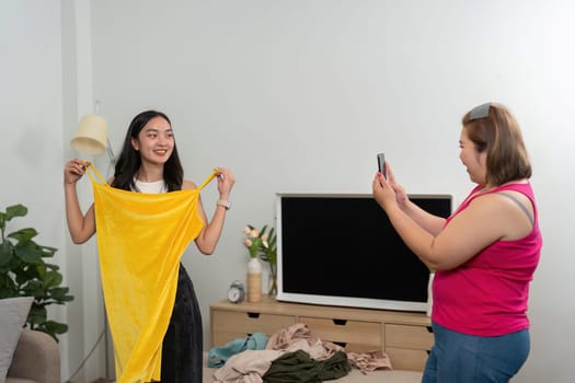 Captured moments of joy as a woman models a striking yellow dress while her friend snaps photos to highlight their unforgettable fun.