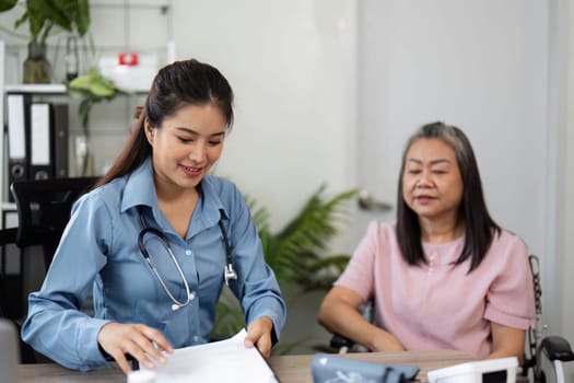 During a home healthcare visit, a nurse reviews important health documents as she consults with her elderly patient, ensuring thorough care and attention to detail.