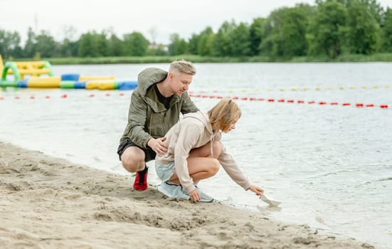 Dad And Daughter Launch Paper Boat In River
