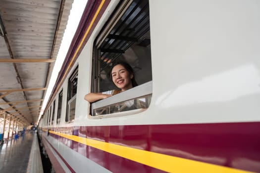 A young woman beams out of a train window, embodying the joy of travel and exploration as she takes in the sights.