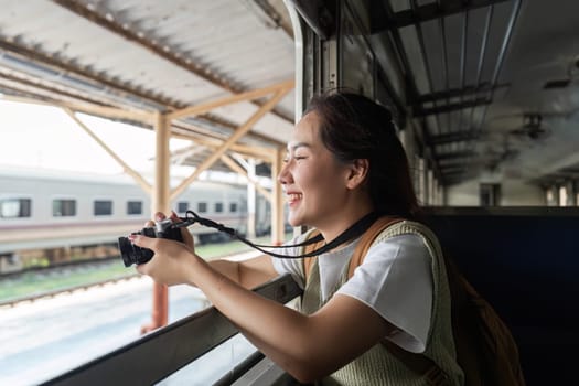 With a camera in hand, a young woman captures the beautiful scenery outside her train window, celebrating travel and adventure.