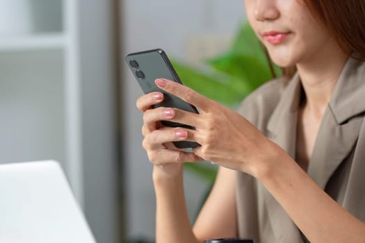 A woman focuses on her smartphone, signifying the integration of mobile technology in daily work routines and communication.