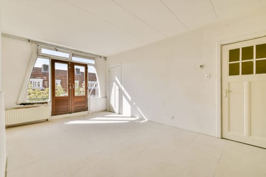 A minimalist interior space with ample natural light pouring in through large windows, featuring white walls and simple design elements.