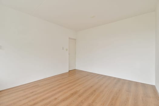 A spacious empty room featuring a light wooden floor and white walls, creating a bright and minimalist atmosphere ideal for various purposes.