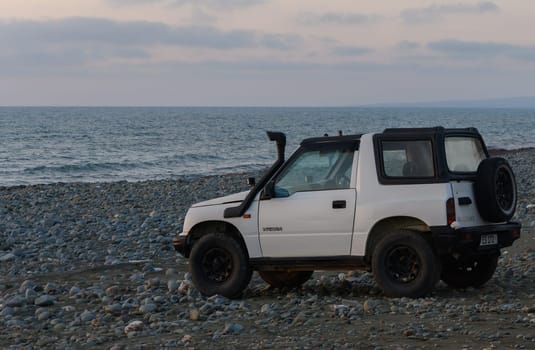Gaziveren Cyprus -16.04.2025 A rugged SUV parked on a pebble-strewn beach, with waves gently lapping the shore under a pastel sky at dusk. A perfect moment for exploration and relaxation by the sea.