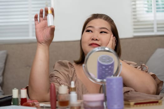 A beauty enthusiast holds a skincare serum, looking contemplative as she enjoys her daily routine, surrounded by various beauty products, capturing the essence of self-care.