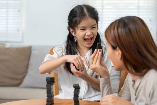 With a big smile, a girl shares an exciting moment with her mother during their game, highlighting the importance of joy and laughter in family life.