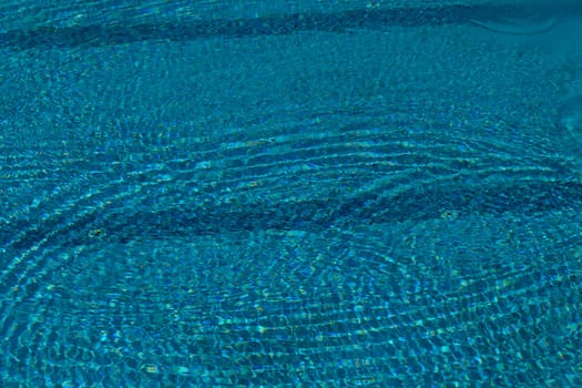 Bright turquoise water dances under the sun, creating shimmering ripples. This tranquil setting invites relaxation on a warm summer afternoon, perfect for enjoying nature's beauty.