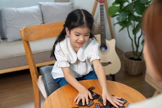 A delightful moment shared between a mother and her daughter as they engage in a game of dominoes, promoting family bonding and interactive play.