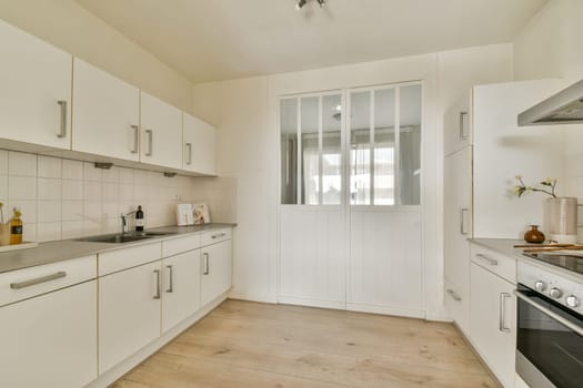 A bright and modern minimalist kitchen featuring sleek cabinets, a stylish stove, and large windows for natural light.