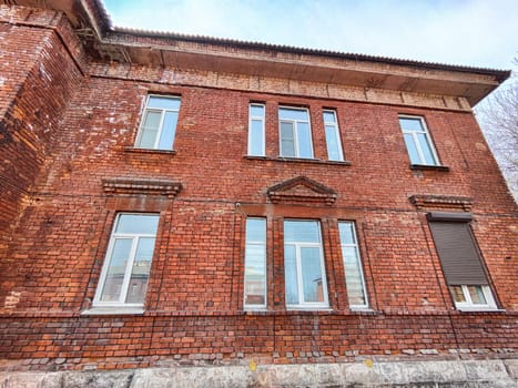 The weathered brick structure features numerous windows and an intriguing facade, located in an urban environment under a clear sky.