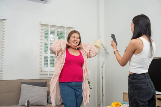 The vibrant atmosphere in the living room highlights a fun outfit showcase, where a woman poses cheerfully for her friend. This image represents the beauty of friendship and confidence in fashion.