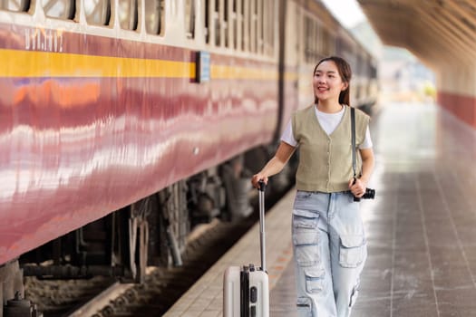 A smiling traveler pulls her suitcase while walking towards a train, excited for her adventure ahead, representing the thrill of travel and new experiences.