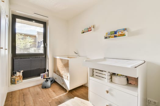 A serene nursery featuring a crib and changing station, complemented by natural light from a large window. The calming design creates a peaceful atmosphere for infants.