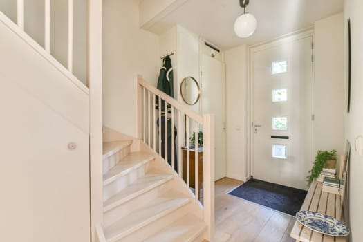 An inviting modern entrance featuring a staircase, stylish decor, and natural light. This design emphasizes simplicity and functionality in a cozy space.